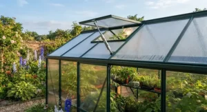 Roof vent opening automatically on a polycarbonate greenhouse to regulate temperature on a warm summer day